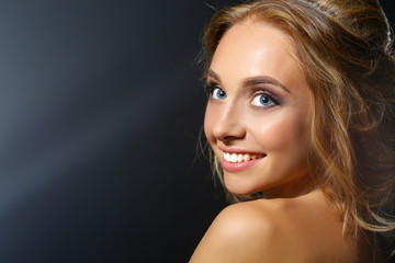 Beautiful woman with curly long hair on dark background