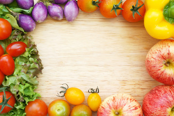 Colorful fresh organic vegetables composing a frame on a wooden chopping board