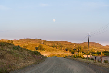 The road among hills and trees sunny summer day.