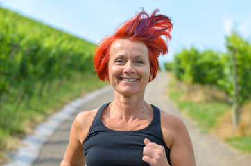 Smiling happy woman jogging in a vineyard