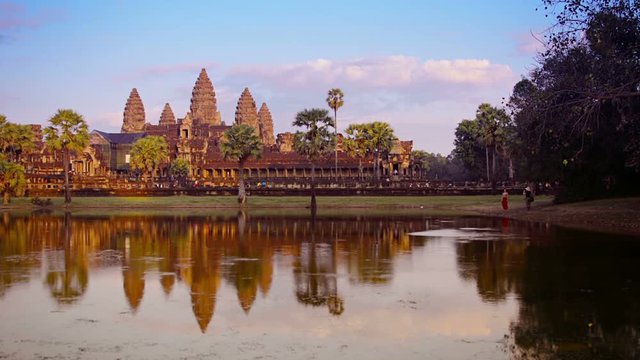 Video 1080p - Late afternoon over Ankor Wat Temple. Tourists and worshipers entering and exiting the temple. The temple is reflected in the moat.