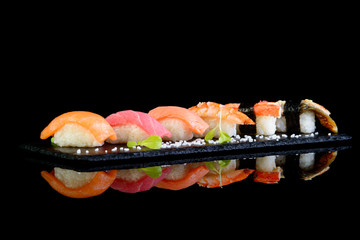 Assorted sushi on a black background with reflection