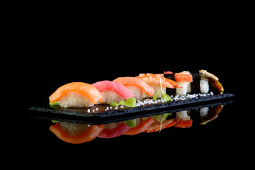 Assorted sushi on a black background with reflection