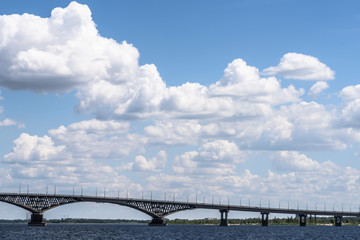 Fototapeta na wymiar Impressive landscape of the beautiful white clouds in the blue sky above the bridge between the cities of Saratov and Engels through the river Volga