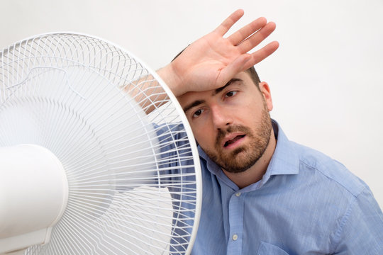 Flushed Man Feeling Hot In Front Of A Fan