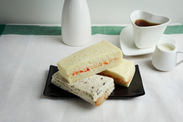 Sandwiches crab stick on the black plate with coffee and milk, b