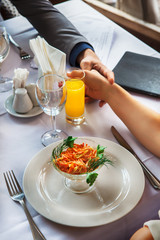 Hands men and women of romantic couple over a restaurant table