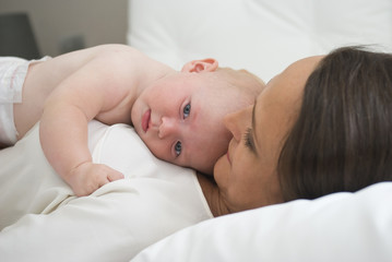 Mother holding baby daughter on bed