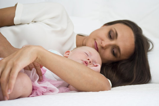 Mother holding baby daughter on bed
