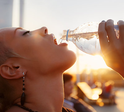 Portrait of beautiful young woman drinking water outdoors