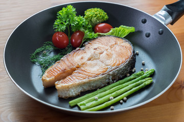 fired salmon in black pan with vegetables