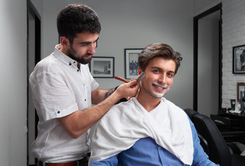 Obraz premium careful barber is shaving the client's beard with razor