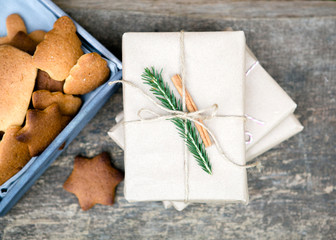 New Year's gift, packed in kraft paper, decorated Christmas tree and cinnamon, next to the cookies