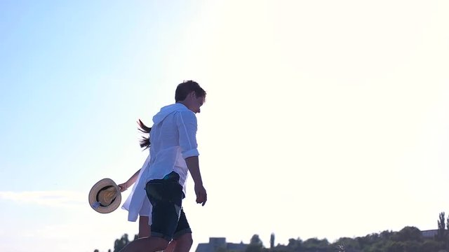 Couple in white clothes running on sky background.
