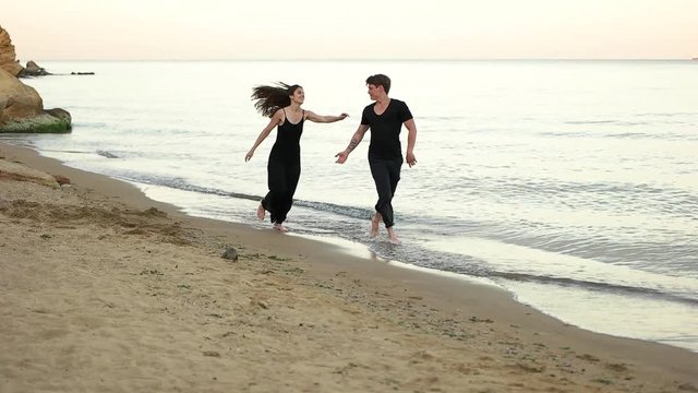 Couple running barefoot on the beach.