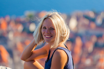 Young female traveler looks to the old city and sea from mountain in Dubrovnik. Summer vacation in...
