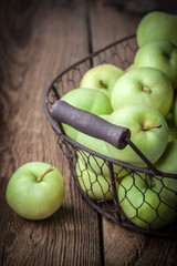 Green apples in a metal basket.
