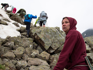 Woman close up with disturbing face against the background of tourists climb the mountain