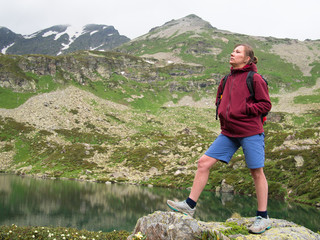 Adult woman standing on a rock with head held against the background of snowy mountains