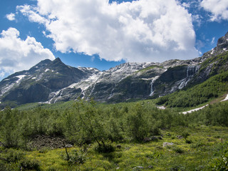 Panorama of North Greater Caucasus mountain range with snow and a waterfall on a background cloudy sky