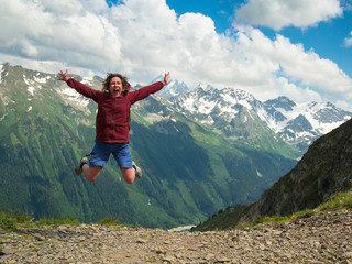 Adult woman jumped up and yells against the backdrop of the mountains of the North Caucasus