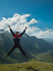 Adult man jumped up and yells against the backdrop of the mountains of the North Caucasus