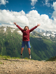 Adult woman jumped up and yells against the backdrop of the mountains of the North Caucasus