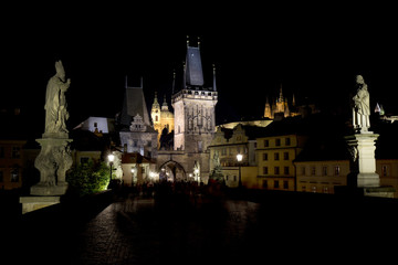 Colorful Prague gothic Castle with St. Nicholas' Cathedral and Bridge Tower from Charles Bridge above the River Vltava in the Night, Czech Republic