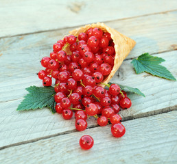 Red currants in waffle cone on rustic wooden background. Dietary and healthy dessert.