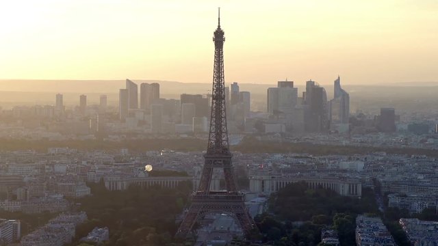 Aerial view of sunrise or sunset over the Paris skyline. Eiffel tower in the foreground with the business district of La Defense in the background.