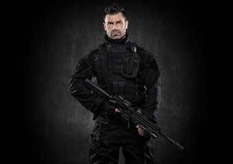 Spec ops police officer SWAT in black uniform studio - obrazy, fototapety, plakaty