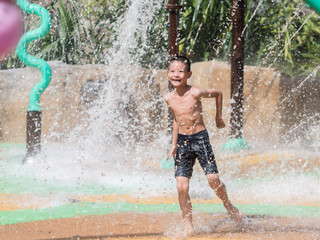 Asian child little boy having fun to play with water in park fountain in summer time