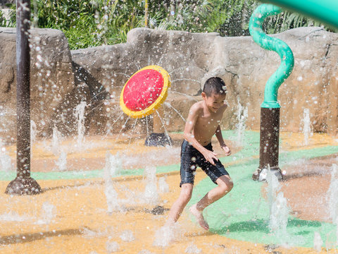 Asian Child Little Boy Having Fun To Play With Water In Park Fountain In Summer Time