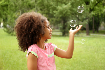 Afro-American little girl catching soap bubbles
