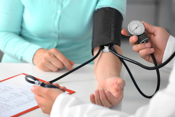 Male doctor measuring woman blood pressure with tonometer