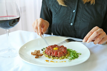 Woman eating tasty steak tartar