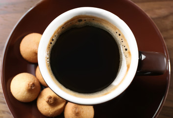 Cup of coffee with cookies on wooden table