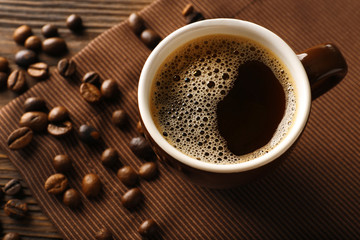 Cup of coffee with beans on wooden table