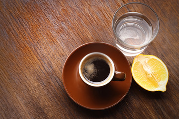 Cup of coffee with lemon and water on table