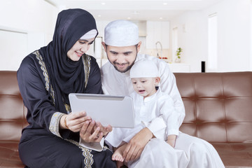 Arabian family playing tablet on sofa