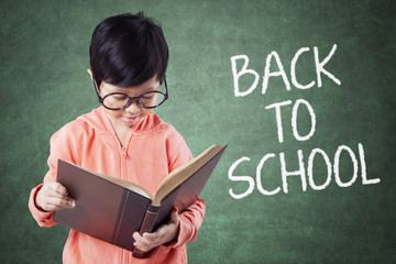 Girl reads book with text of Back to School