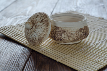 Empty clay pot with lid on wooden table