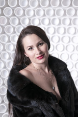 Portrait of long-haired girl in a fur coat on naked body