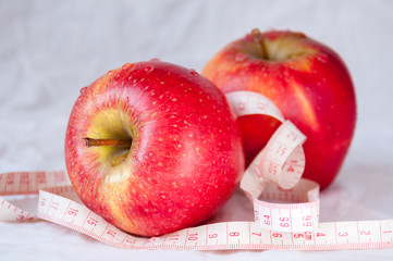 Two red apple among white tape measures