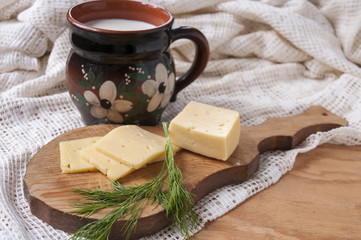 Cheese, dill and jug of milk on the table
