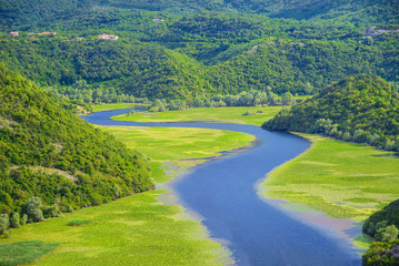 Meandering Rijeka Crnojevica river behind green mountains in Skadar Lake National Park, Montenegro,...