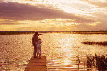 Father and daughter by the lake at sunset
