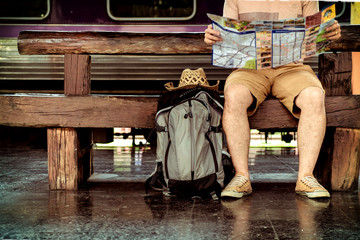 Young man traveler sitting with backpack look searching location map