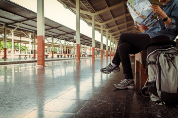 Young girl traveler sitting with backpack look searching location map