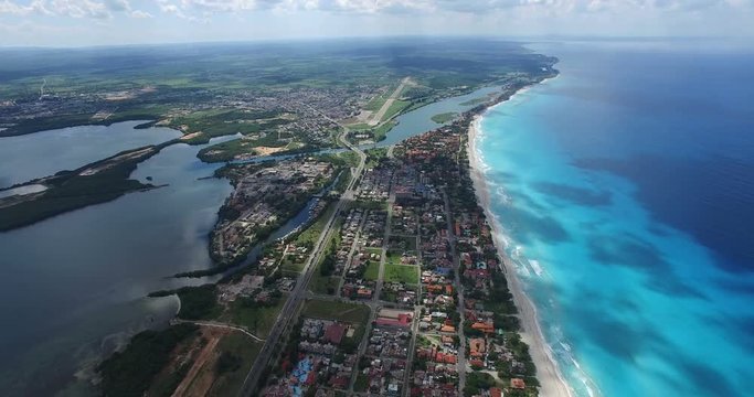 VARADERO, CUBA - MAY 21, 2016: Drone flies over tropical island on a clear day. Calm Atlantic Ocean and the bay. Flying over the city. On the road going car, close to the shore. Height of 500 meters